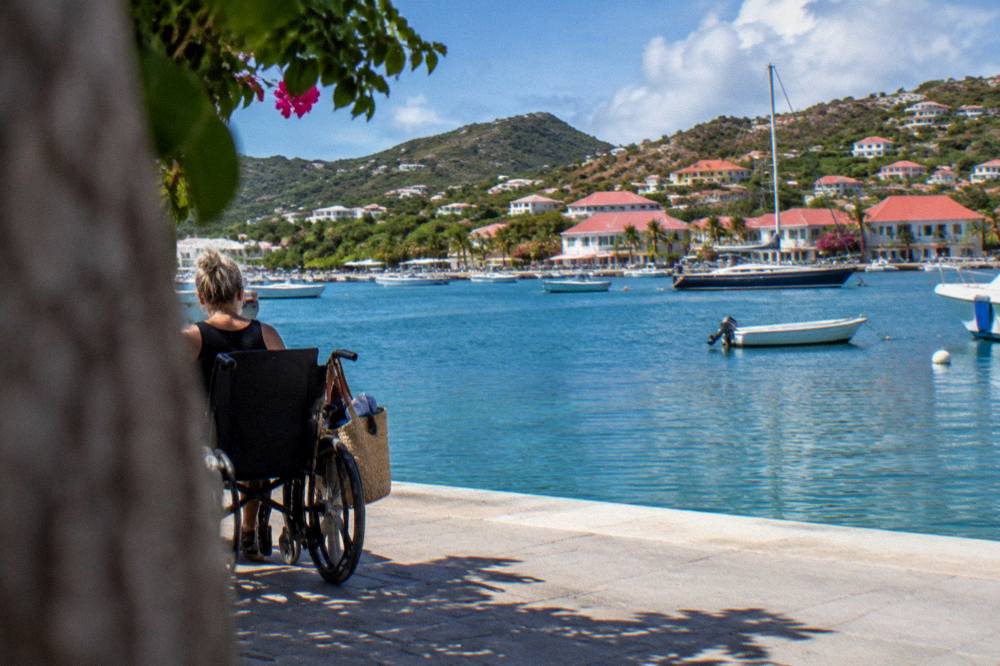 Wheelchair and beach bag on a flat seafront promenade beside calm water
