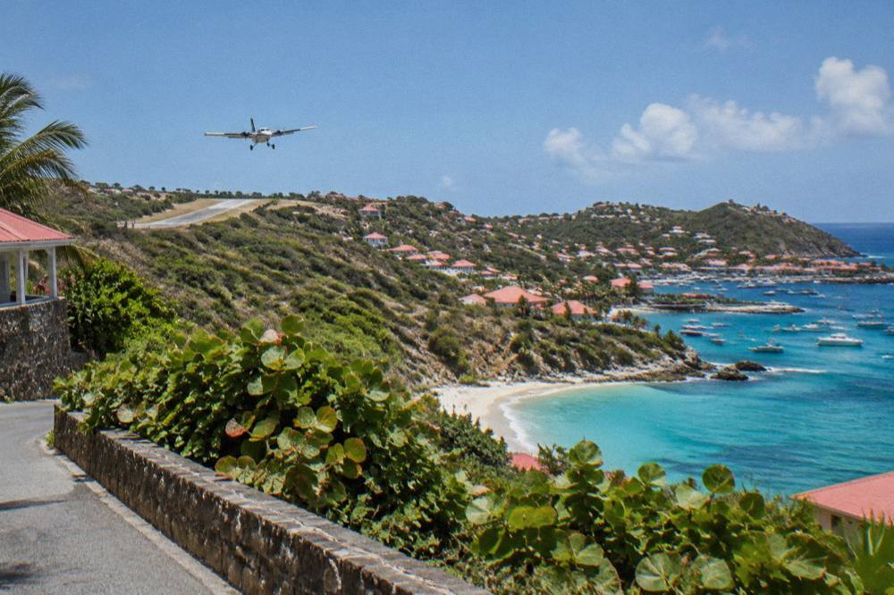 The departure board and small terminal building of a Caribbean island airport