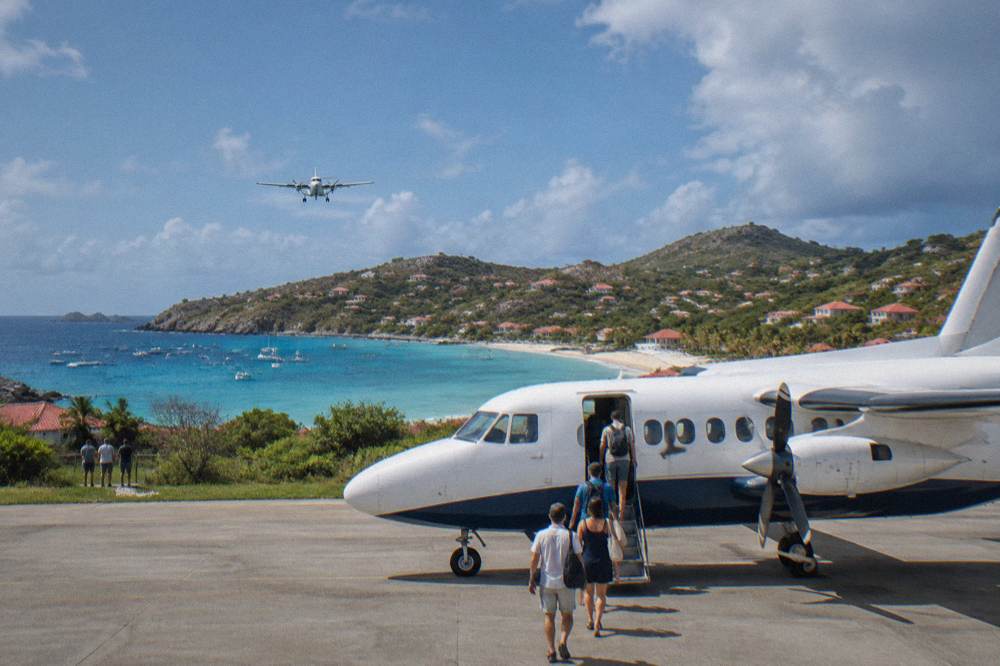 Passengers boarding a nine-seat turboprop airplane on a warm airport apron