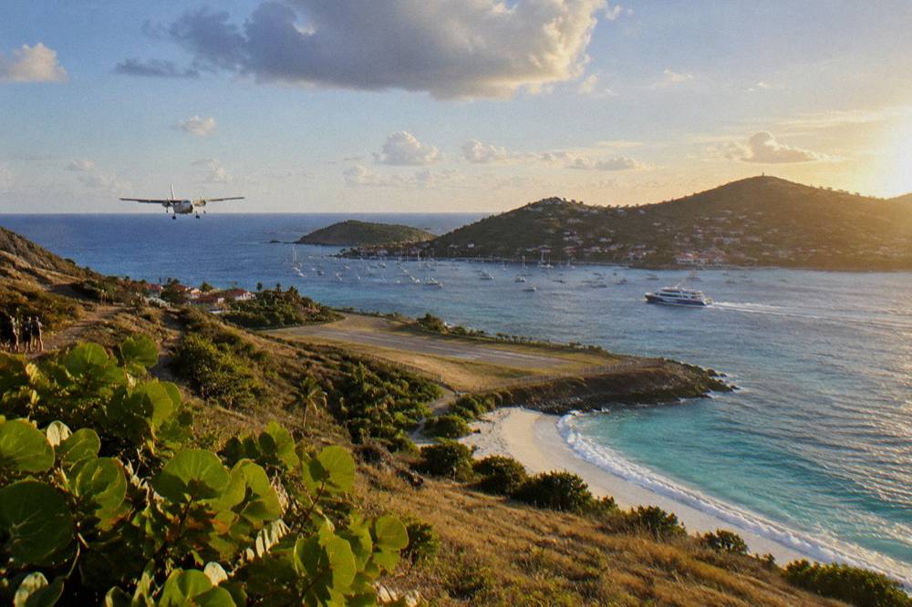 A passenger ferry cutting across open blue water toward a green island coastline