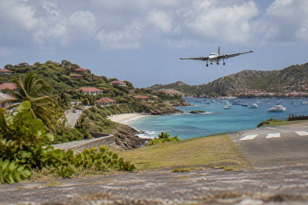 A narrow coastal road winding between palm trees and turquoise water on a small Caribbean island
