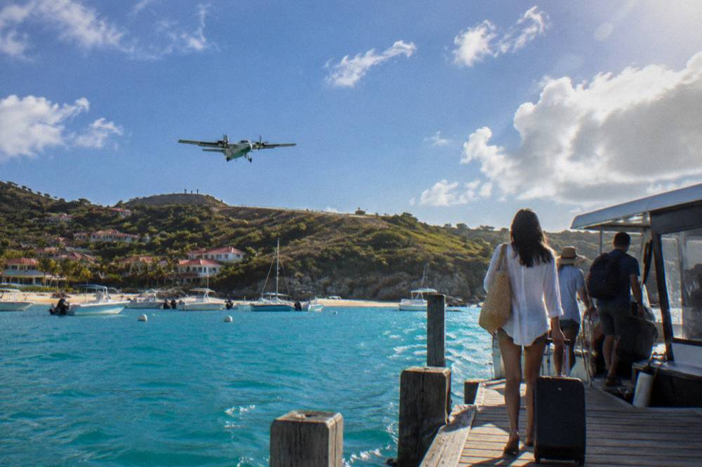 Travelers with luggage boarding a small ferry at a Caribbean marina dock