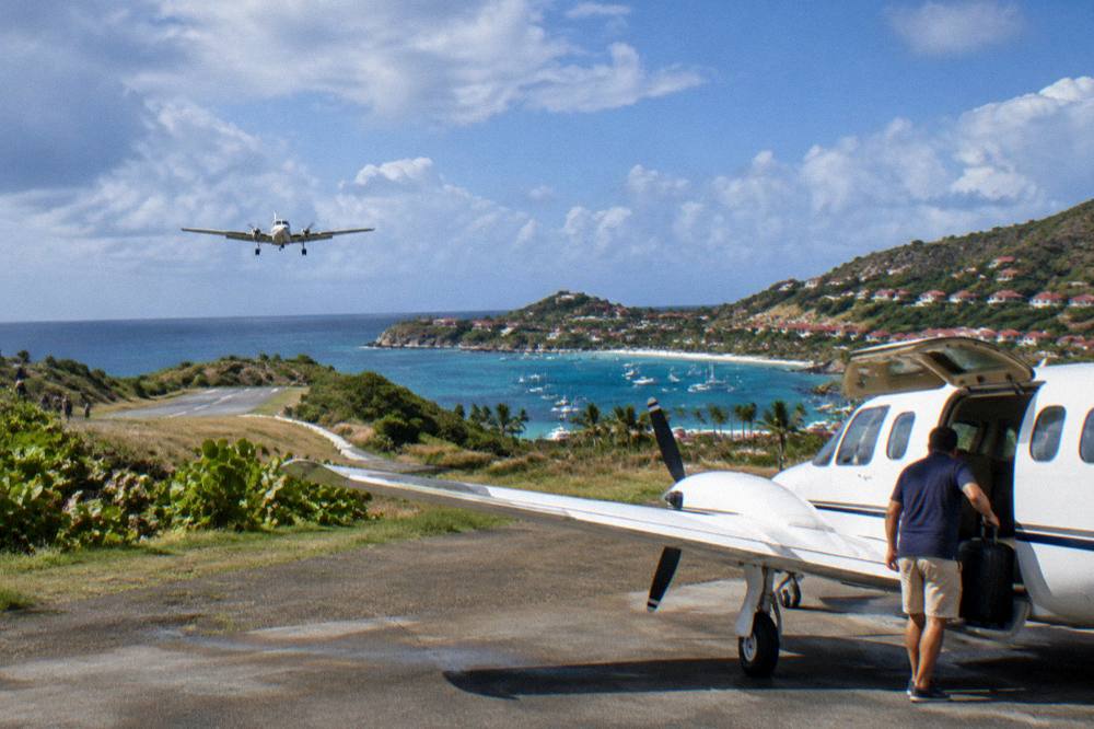 A traveler lifting a small suitcase into the cabin of a small propeller aircraft