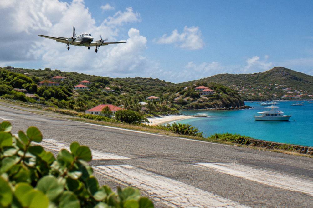 A private charter boat anchored in a quiet Caribbean bay with green hills behind