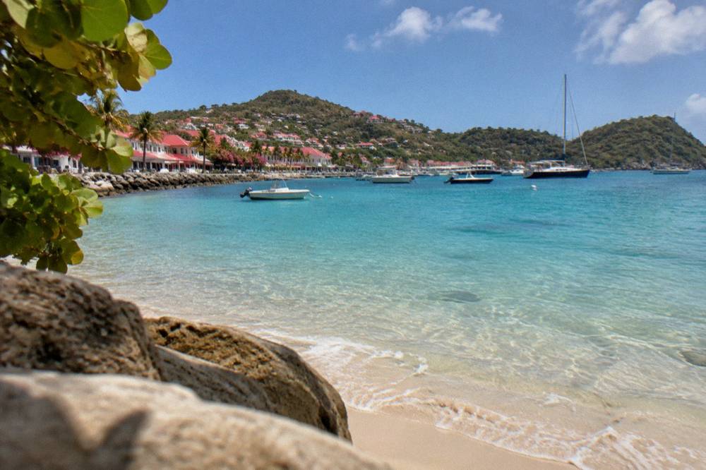 Clear shallow water over a sandy bay with a green headland beyond