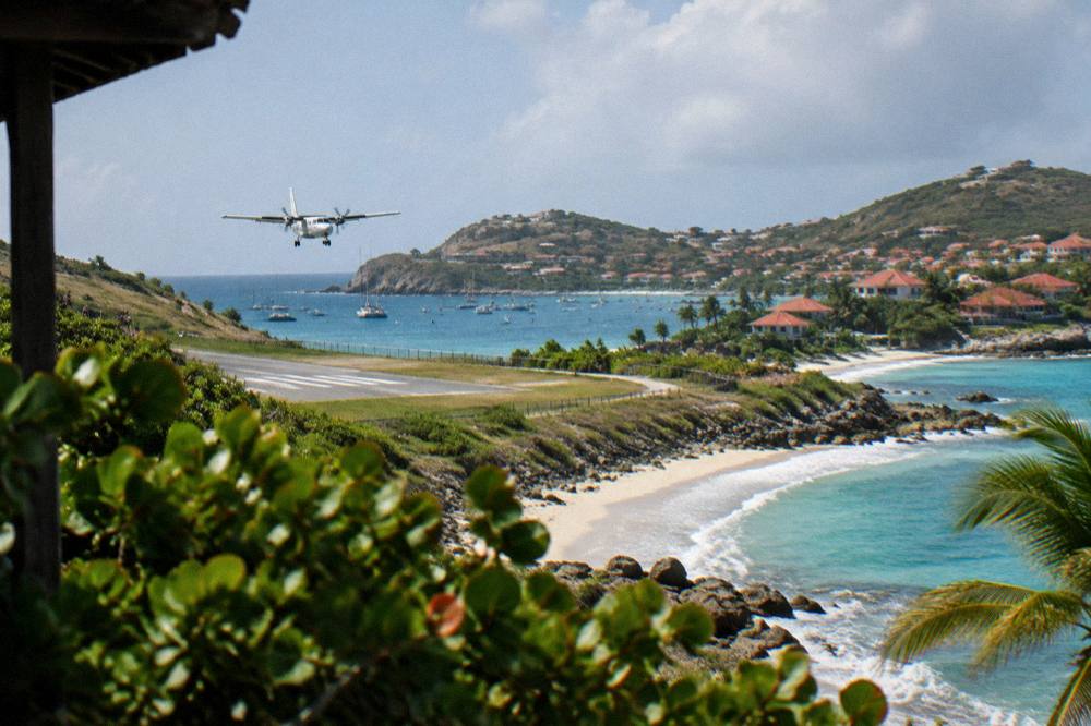 A small turboprop aircraft on a short runway beside a beach