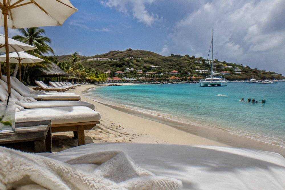 A catamaran at anchor in a quiet bay with people snorkeling near the shore