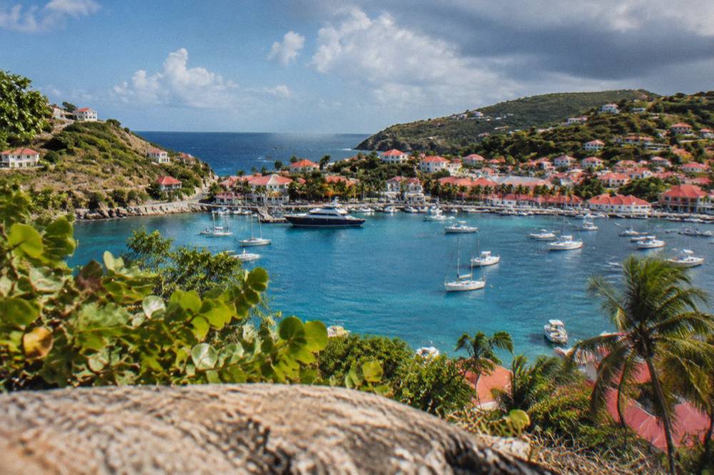 The harbor town of Gustavia with red roofs and boats, seen from a headland