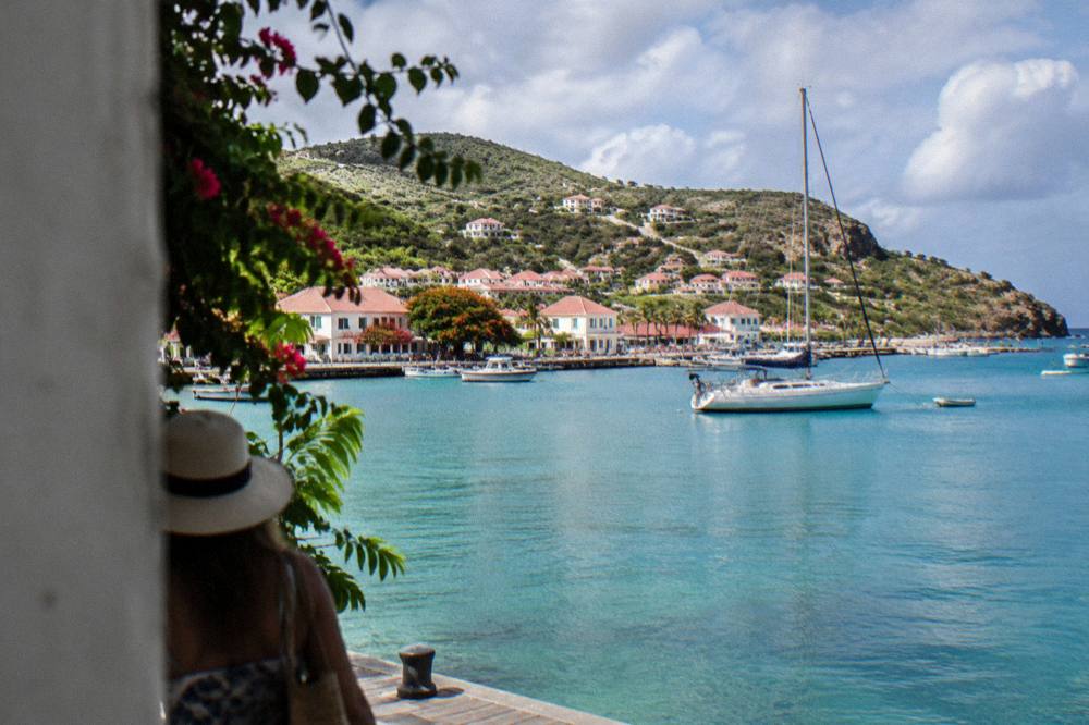 A sailboat anchored in a green bay on St Barts with a rocky headland