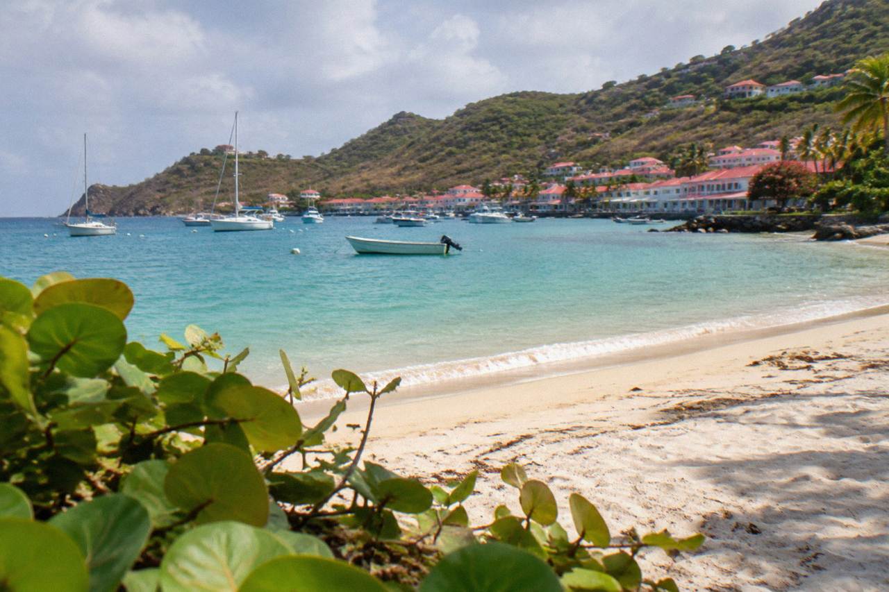 A quiet Caribbean beach on St Barts with turquoise water and green hills behind the sand