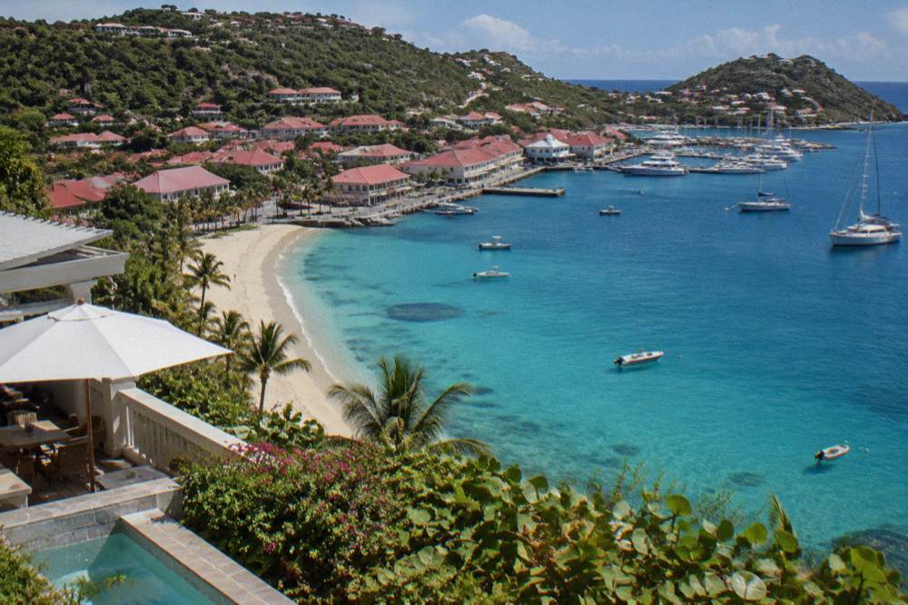 A lone beachfront hotel terrace above a wide sandy bay with palms and clear water