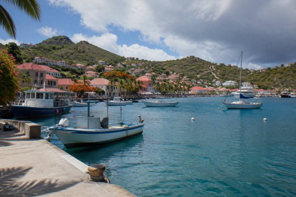 A small ferry and fishing boats moored in a Caribbean harbour town with red roofs