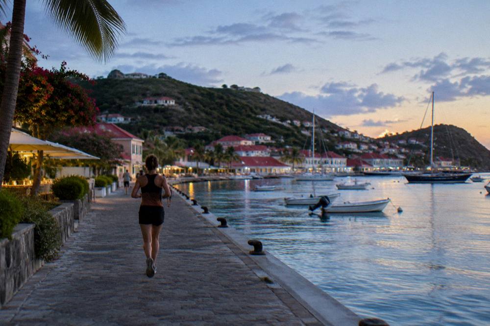 A hotel terrace at golden hour overlooking a calm Caribbean bay with a few sailboats
