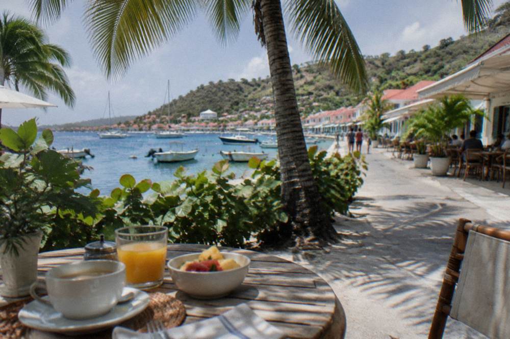 An outdoor breakfast table under palm trees in morning light