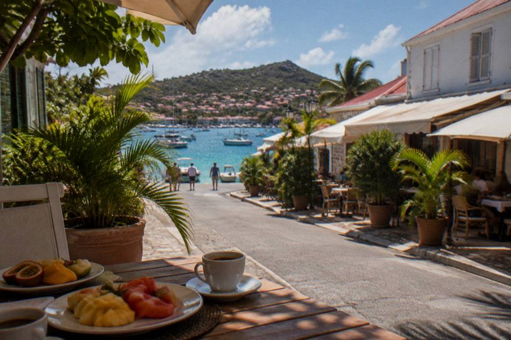 A simple beachside table with fruit plates and coffee in the shade