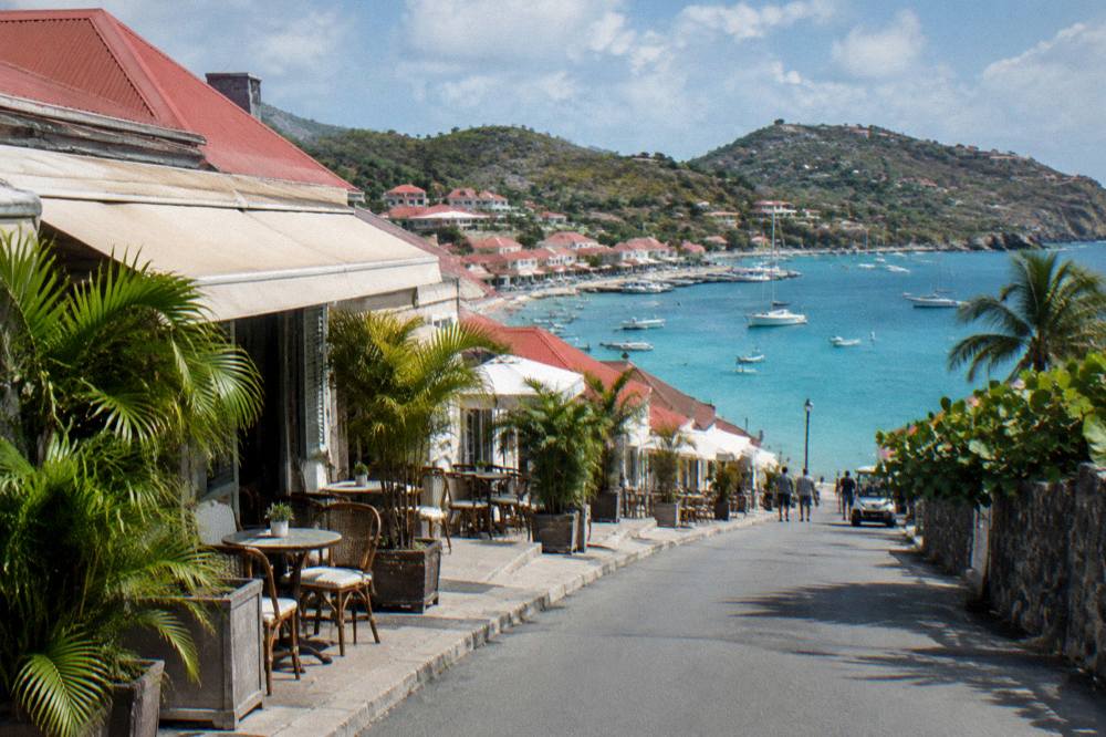A hillside view of red rooftops above a Caribbean harbor in morning light