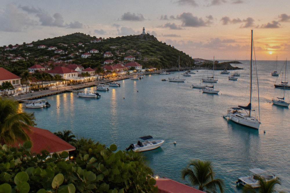 A harbour town at dusk with lights along the quay and boats at anchor