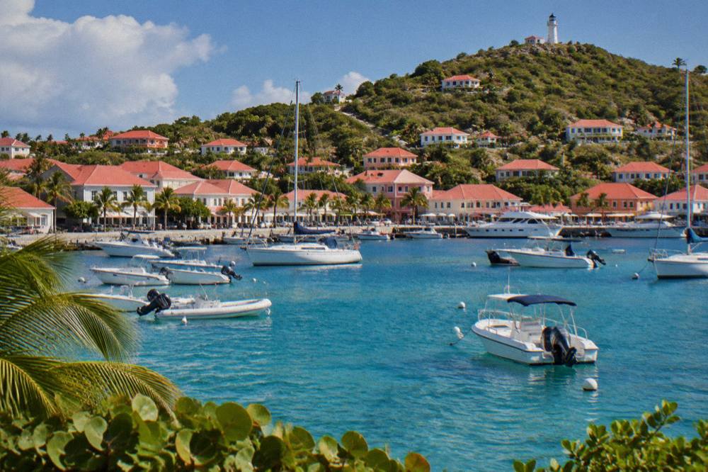 Red-roofed Caribbean houses on a green hillside above turquoise water