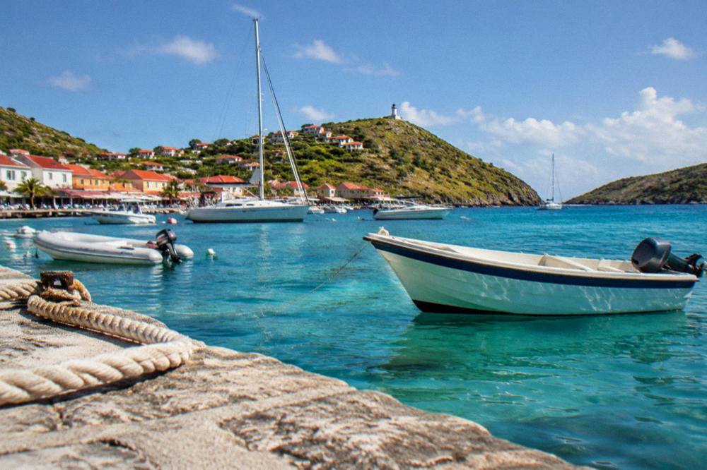 A sailboat anchored in a quiet bay with clear water and green headlands