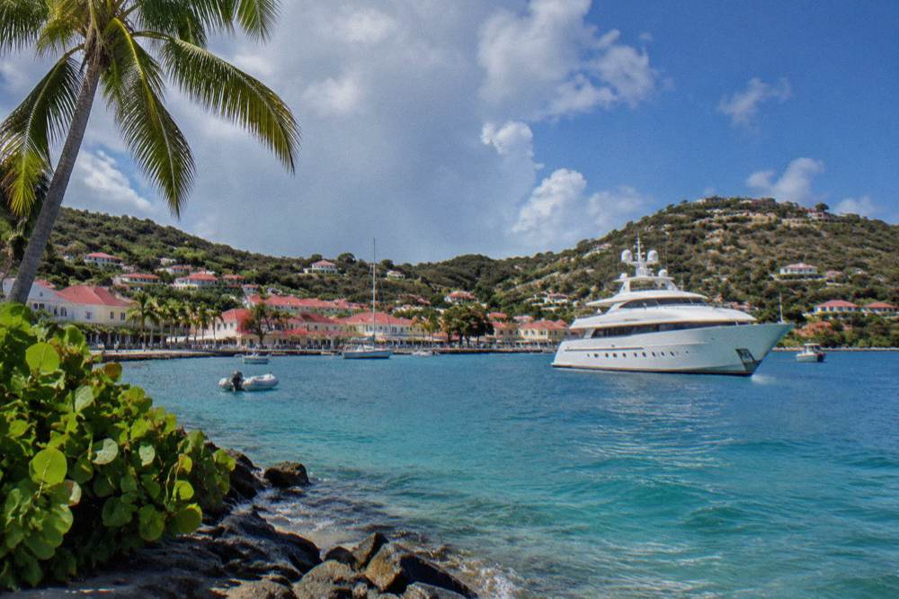 A large white yacht at anchor in a Caribbean bay