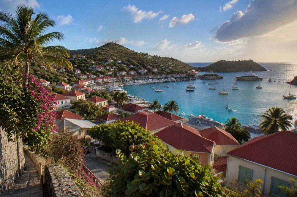 Hillside view over red rooftops toward a blue Caribbean bay