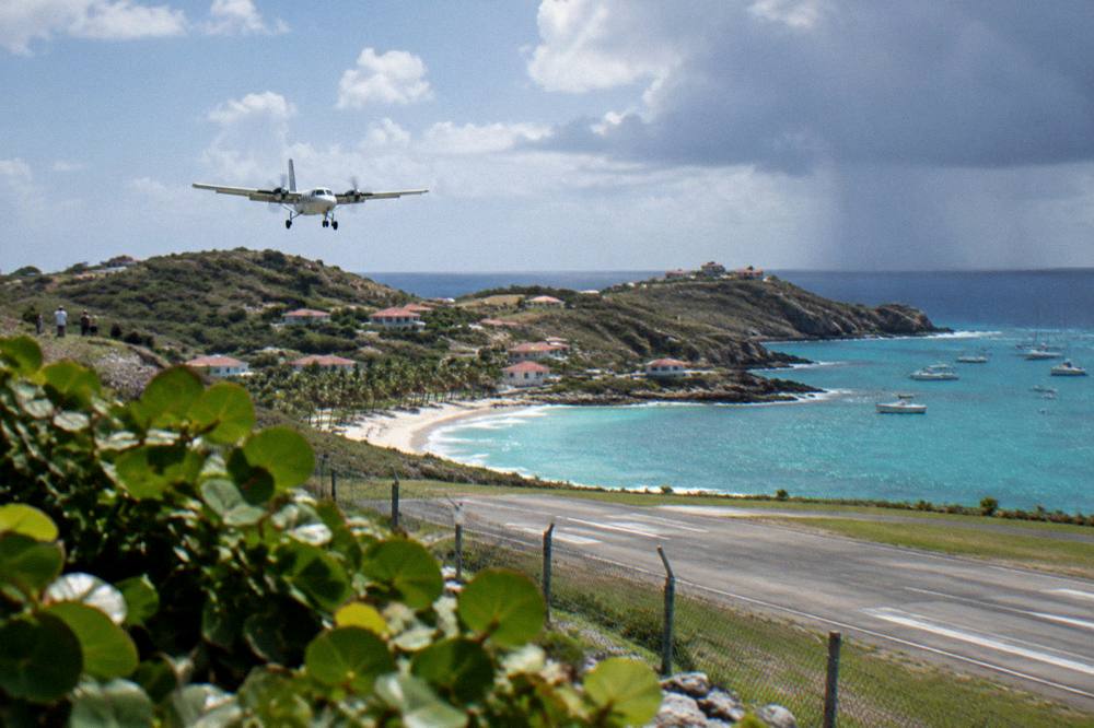 A small turboprop aircraft on a short runway beside a beach
