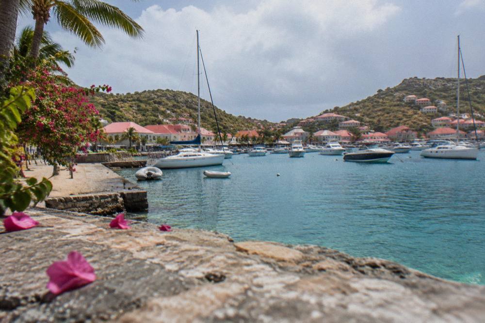 Sailboats and motorboats at moorings inside a rocky bay