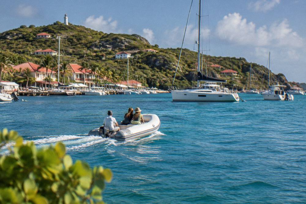 Tender boat crossing the bay toward the Gustavia waterfront with anchored yacht beyond