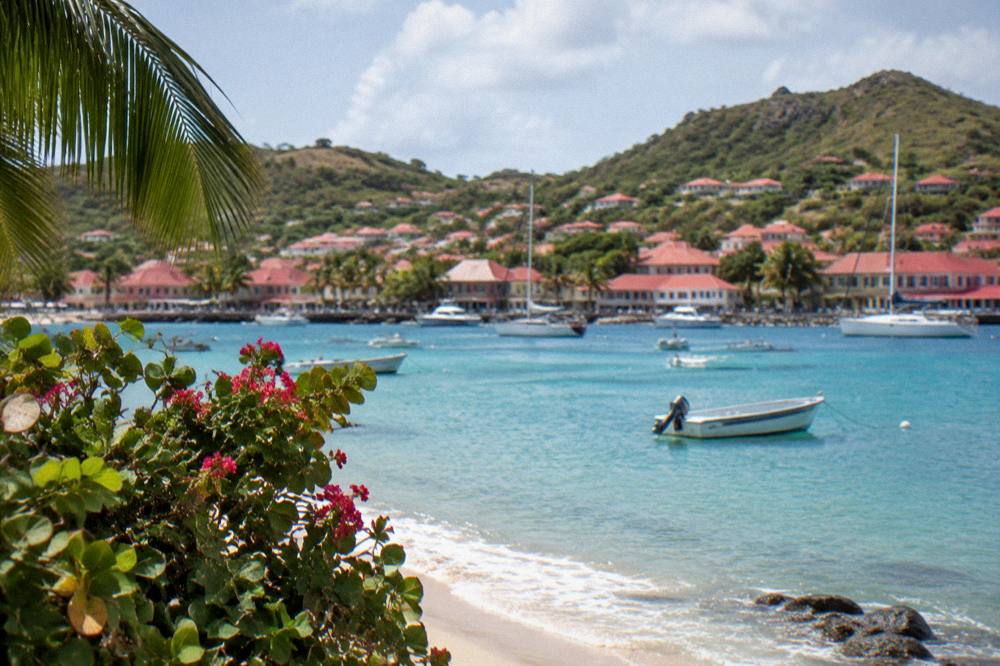 White sand beach with turquoise water and green hills on the coast of St Barts