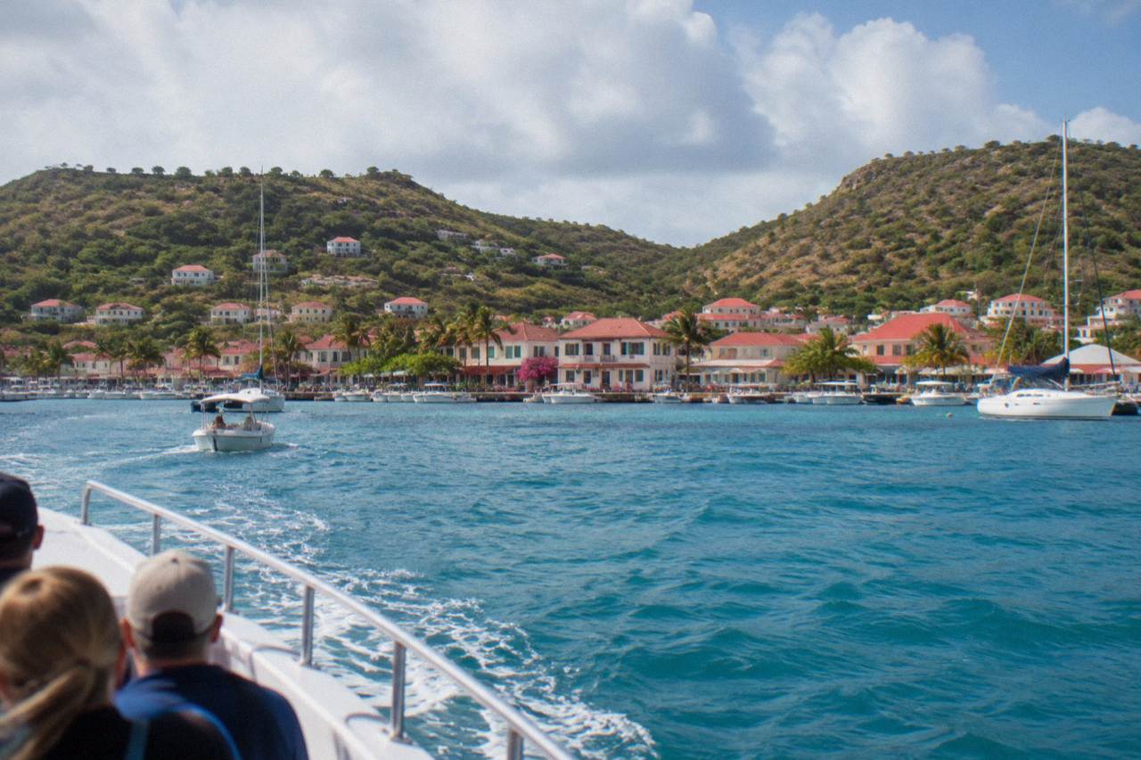 Cruise ship tender boat approaching the harbor front of Gustavia on St Barts with hills behind the town