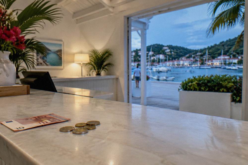 A whitewashed hotel reception desk with a bill and euro coins on the counter