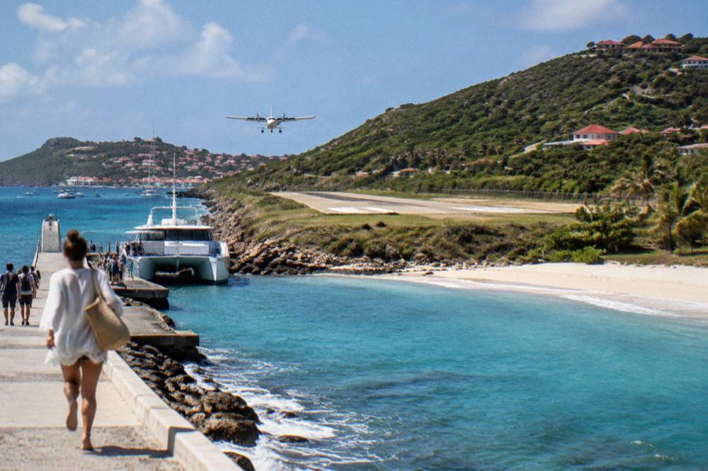 A ferry terminal jetty with a moored catamaran and passengers carrying bags