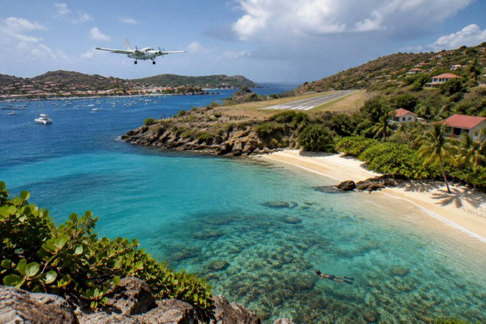 A clear shallow bay with a snorkeler swimming above coral and small fish