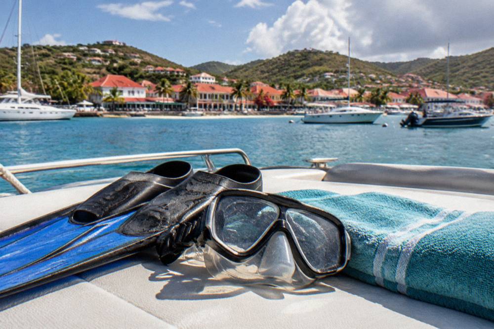 Snorkel mask and fins resting on a boat deck beside a folded towel