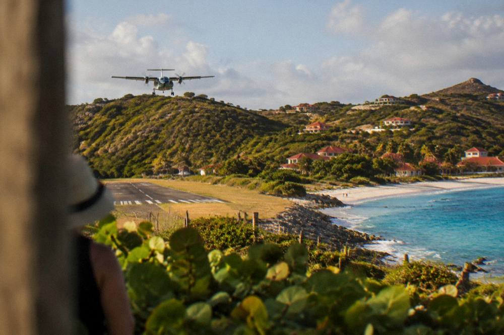 Small turboprop aircraft on a short runway beside a beach with hills behind