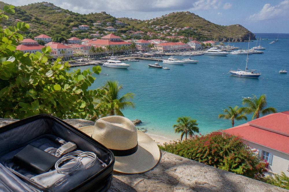 A power bank and cables packed in an open carry-on bag beside a sun hat