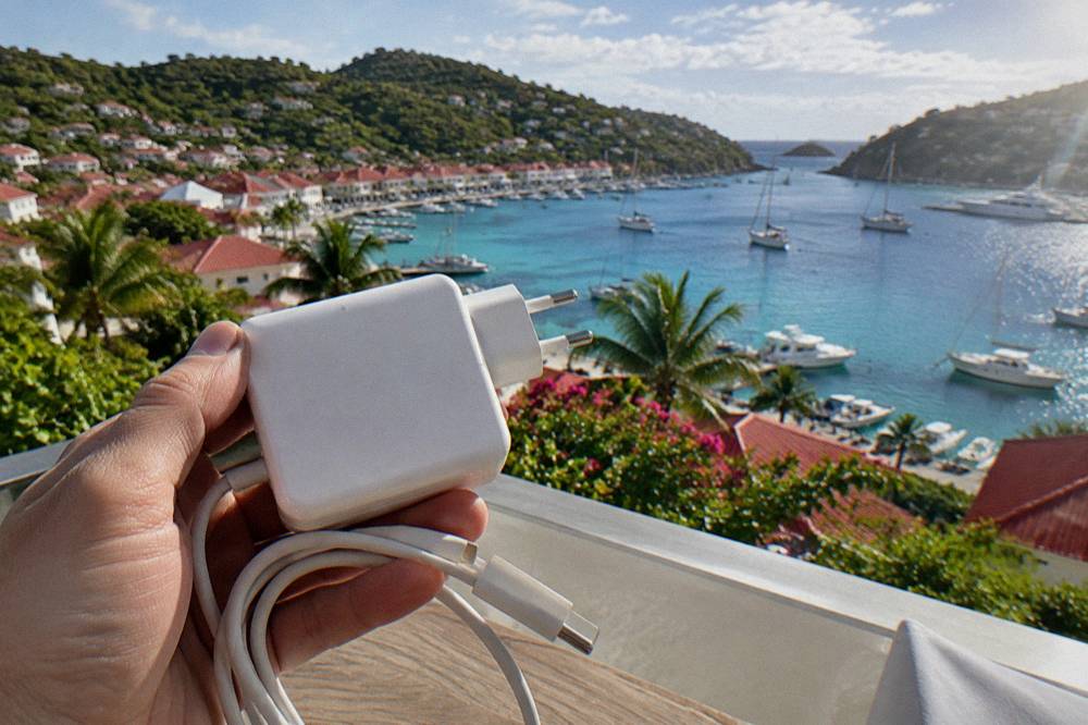 A laptop charger block held in a hand showing its input label in daylight