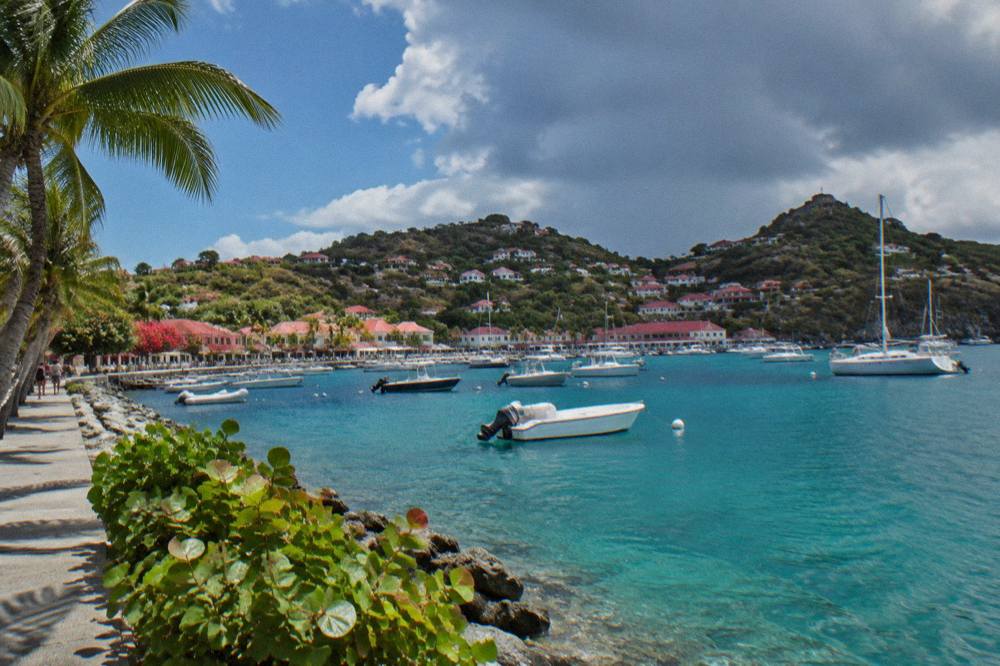 Dark clouds and sunshine over a turquoise Caribbean bay with palm trees