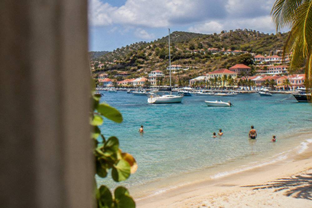Families swimming in clear shallow water beside a white sand beach on St Barts