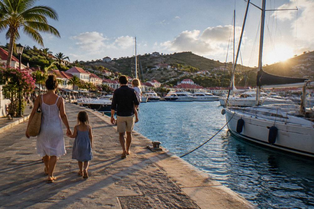 A family walking along a harbor quay in Gustavia with yachts moored alongside