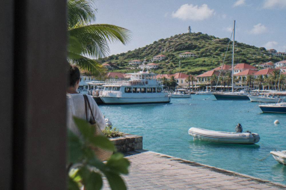 A white passenger ferry moored at a small Caribbean marina with hills behind