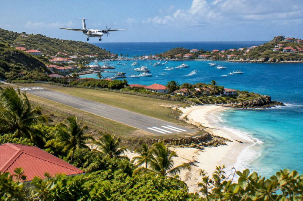 A small twin-engine turboprop aircraft on a short runway beside a beach