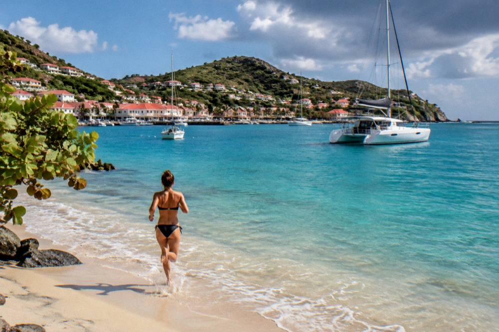 A catamaran anchored in a quiet turquoise bay on the coast of St Barts in late afternoon light