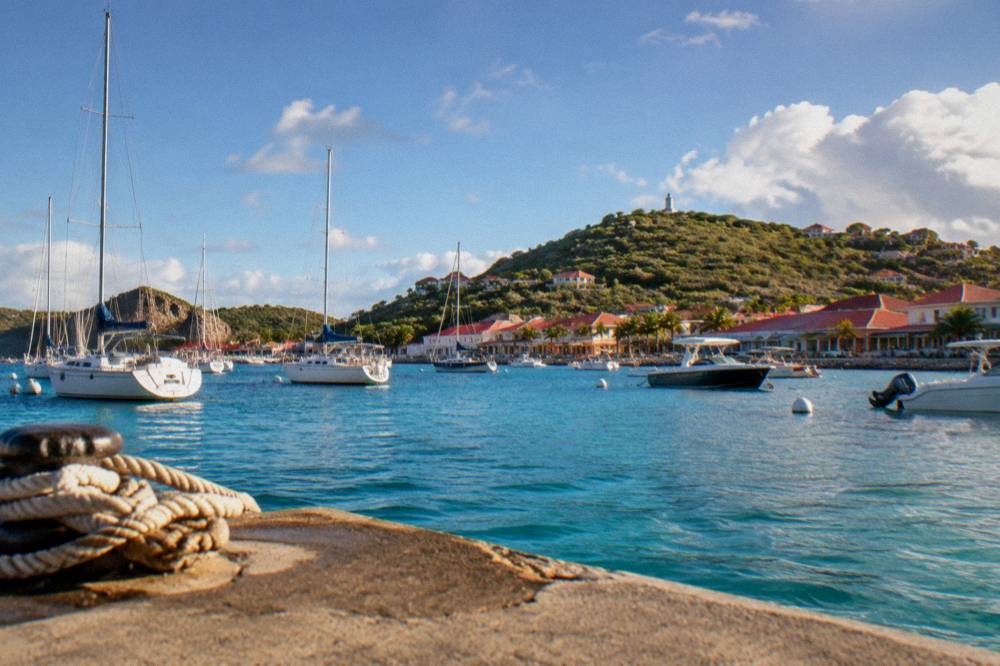 A harbour town with red roofs and small boats at anchor seen from the water