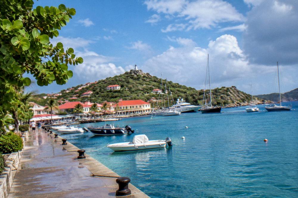 Calm turquoise Caribbean water near a rocky headland under scattered clouds