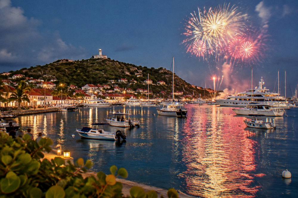 Fireworks bursting above a harbour full of lit-up yachts at night