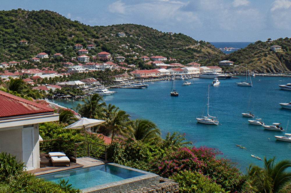 A hillside villa with a terrace pool overlooking a Caribbean bay at midday