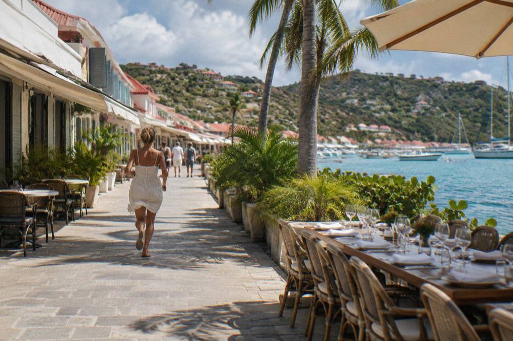 A long leisurely lunch table with wine glasses beside the sea