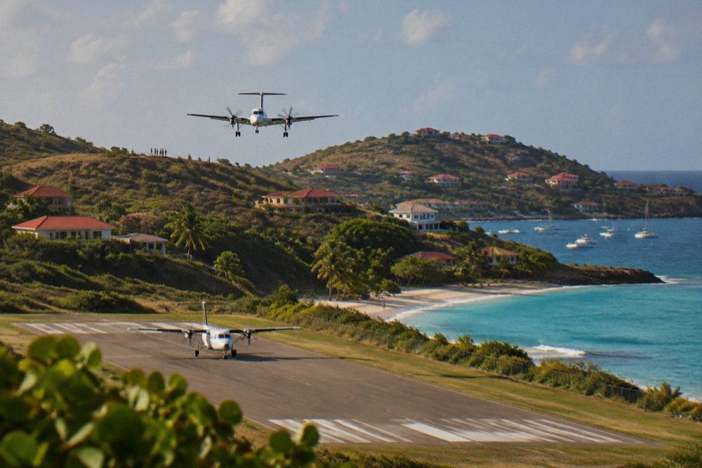 A small turboprop aircraft on the short runway at St Barts airport beside the beach