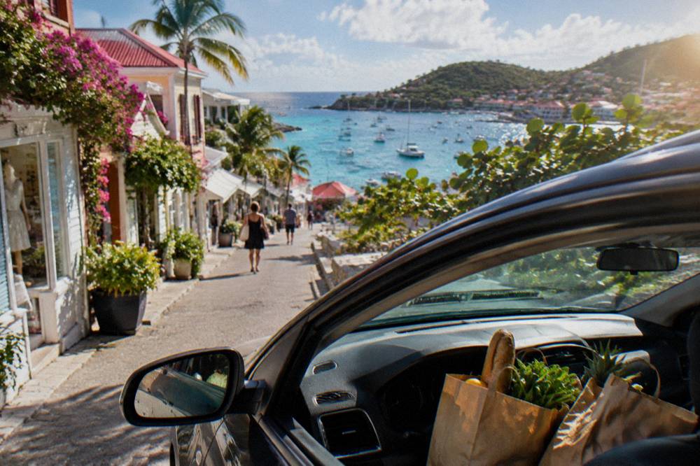 Paper grocery bags on a car seat with a view of turquoise Caribbean water beyond the windshield